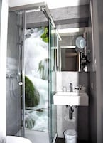 Un baño moderno con ducha envuelta en vidrio, un lavabo y un espejo.