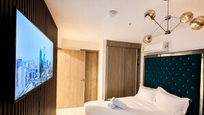 Une chambre d’hôtel équipée d’un lit, d’un téléviseur fixé au mur, d’une armoire et d’un luminaire au plafond.