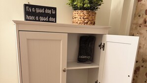 Un tocador de baño con un cartel que dice 'It's a good day to have a good day', una planta en maceta, un neceser de maquillaje y un letrero que indica no tirar nada más que papel higiénico.