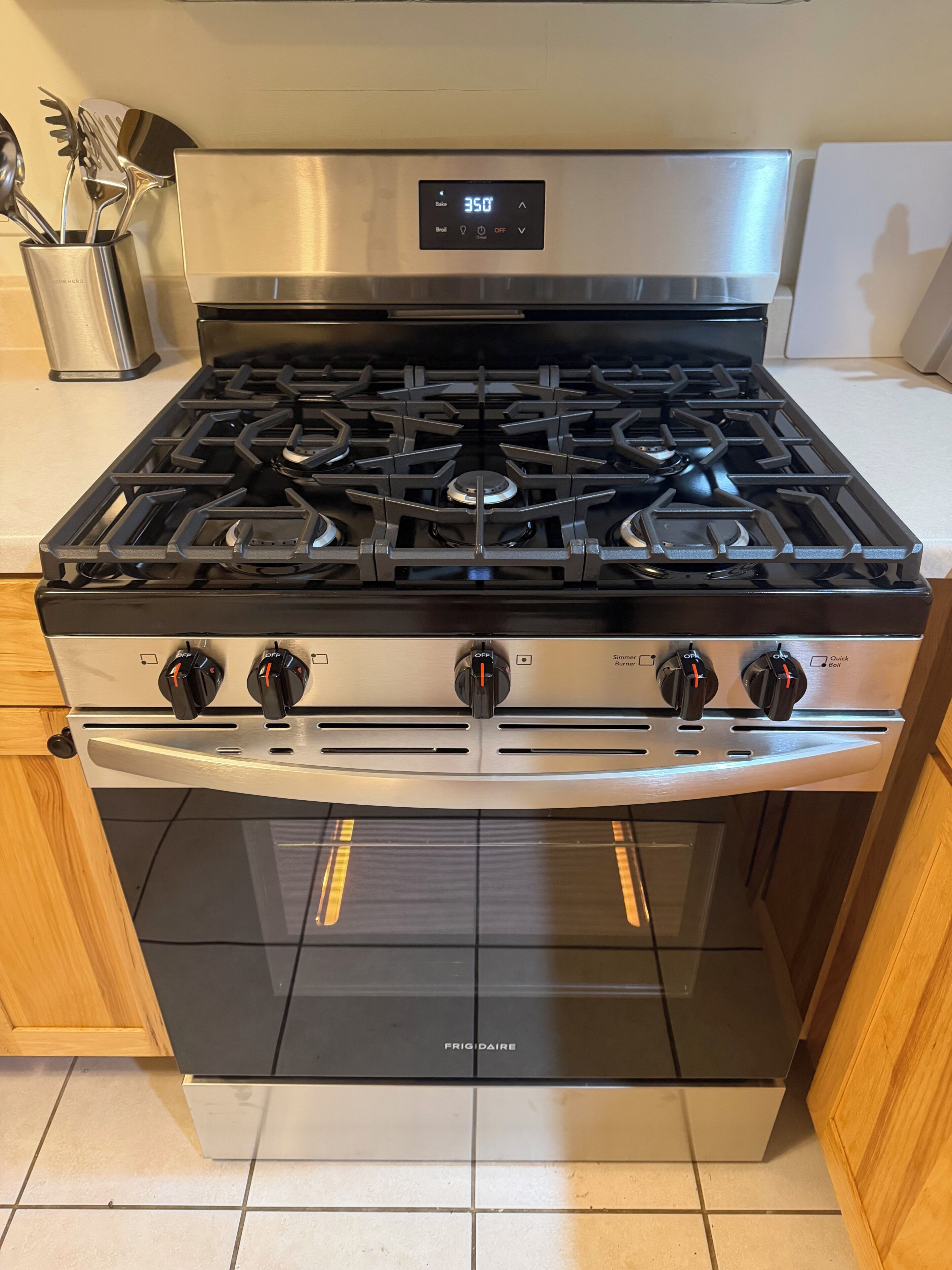 A stainless steel kitchen with a gas stove, oven, and a digital display.