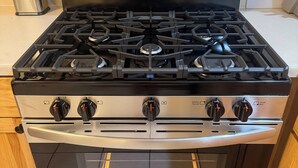Una cocina de acero inoxidable con estufa a gas, horno y pantalla digital.