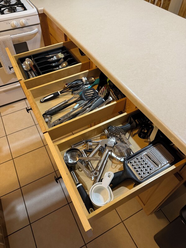 Un cajón de cocina con diferentes utensilios y herramientas.