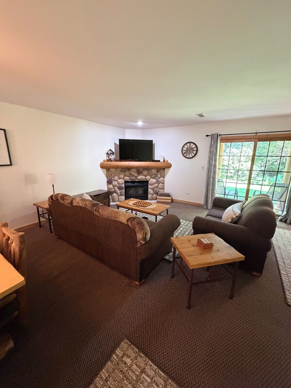 A living room with a stone fireplace, a television, a sofa, and a dining table.