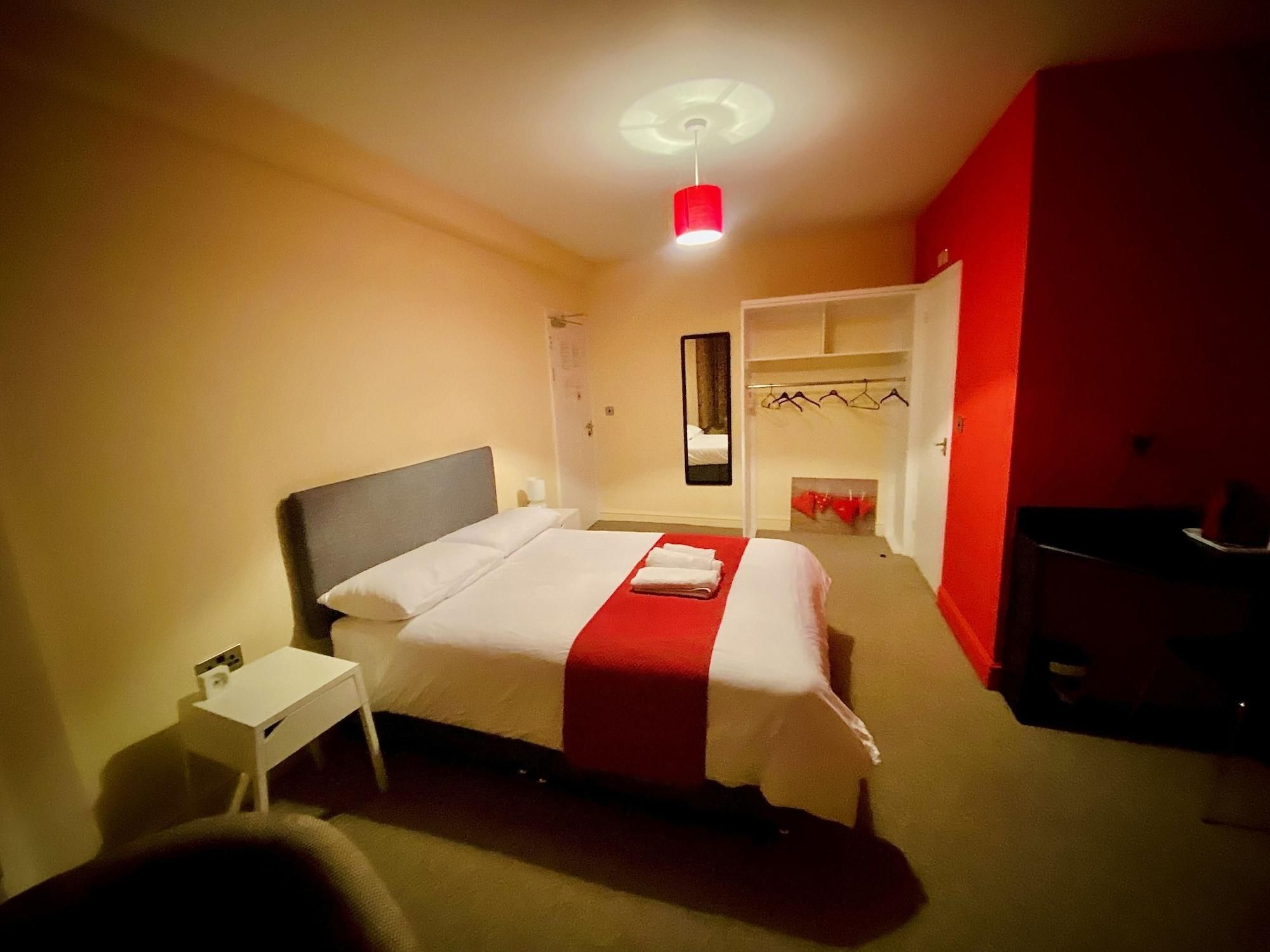 A hotel room with a bed, a small bedside table, a wardrobe, and a mirror.