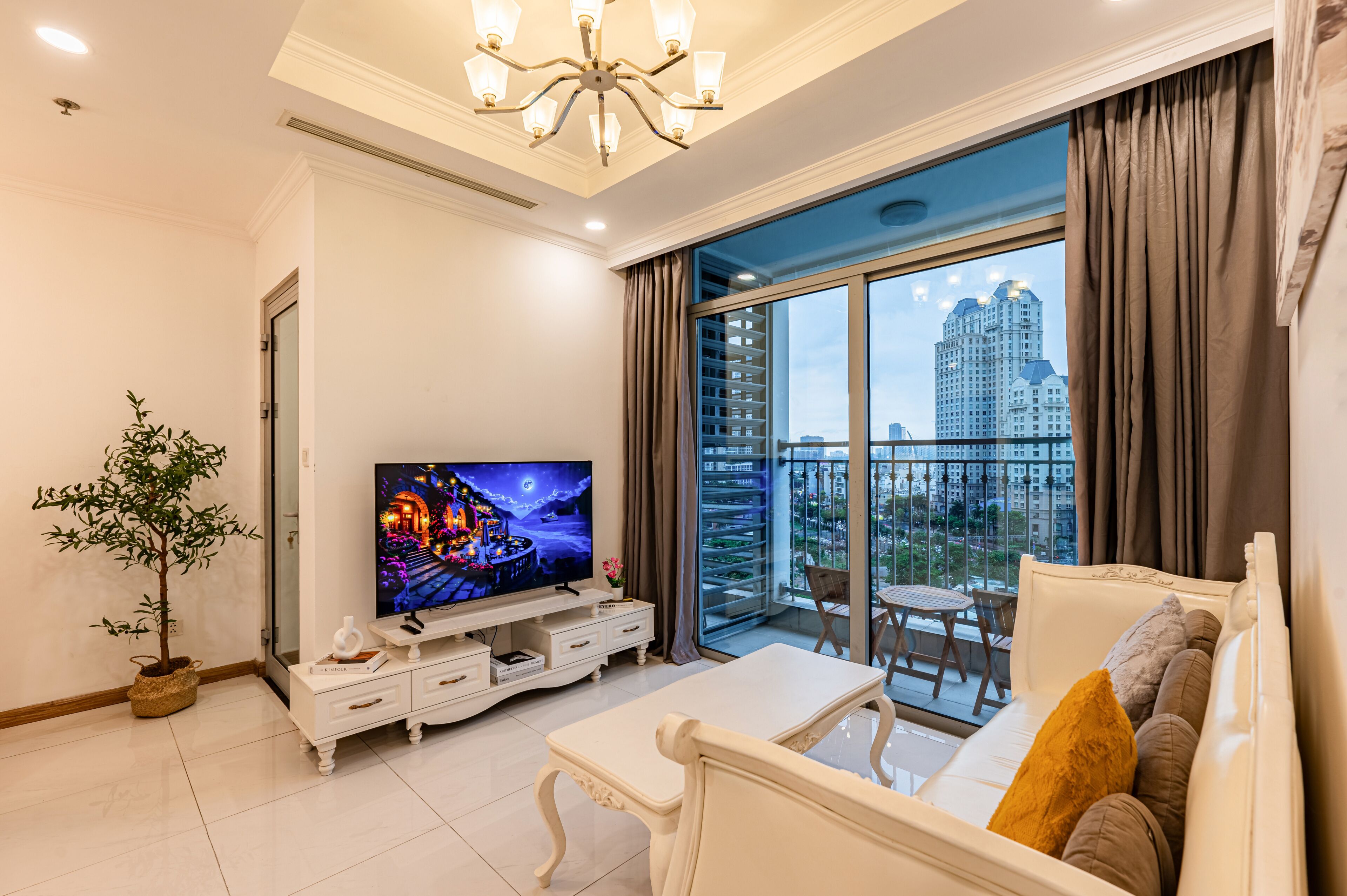 Una sala moderna con televisor de pantalla plana, una mesa de comedor, un sofá y un balcón con vista a la ciudad.