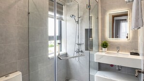 A modern bathroom with a glass-enclosed shower, a toilet, a sink with a mirror, and a towel rack. - Danang Boutique Apartment | 02 Private Balcony 5 min to the Beach (Đà Nẵng)