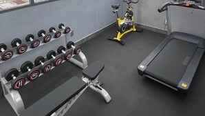 A gym with a treadmill, stationary bike, and dumbbells. - Danang Boutique Apartment | 02 Private Balcony 5 min to the Beach (Đà Nẵng)