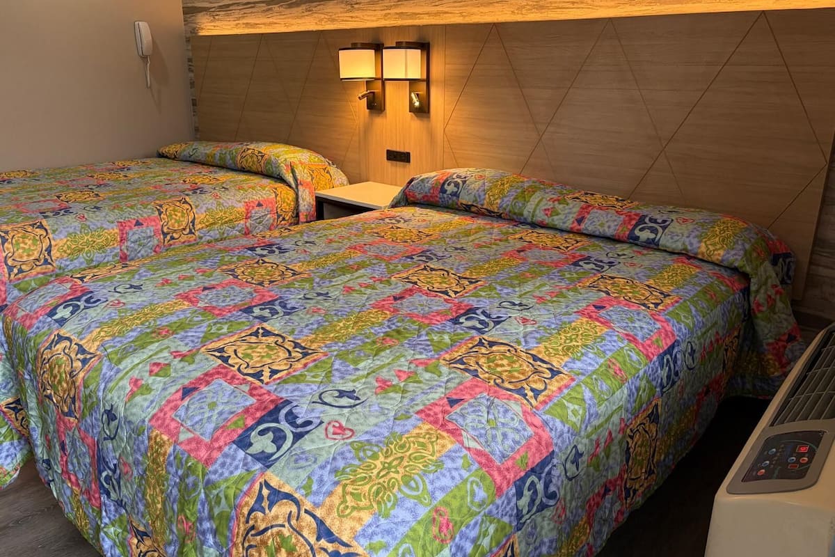 Habitación de hotel con dos camas, un teléfono en la pared y un calentador.