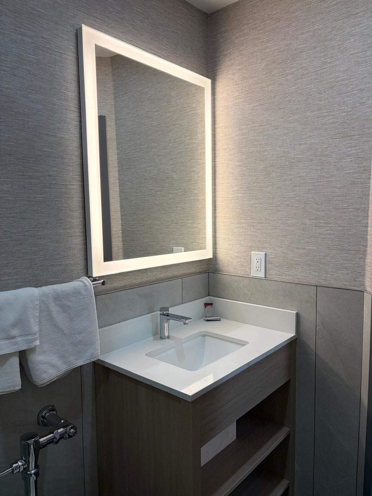 A bathroom with a white sink, a mirror, and a towel rack.