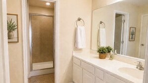 Ein Badezimmer mit Dusche, Waschbecken, Spiegel und Handtuchhalter.