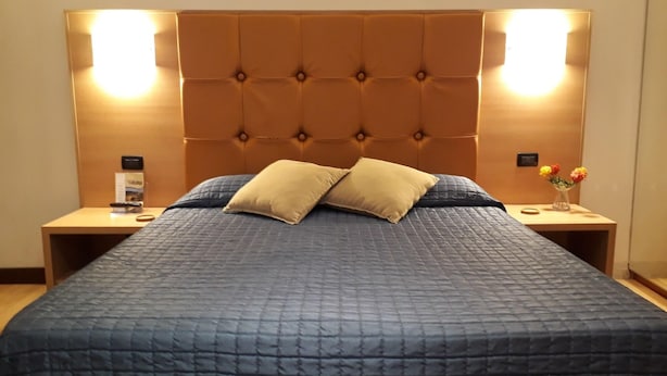 A bed with a tufted headboard, two bedside tables, and a vase with flowers.
