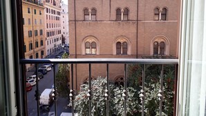 A view from a balcony overlooking a street with parked cars and buildings.