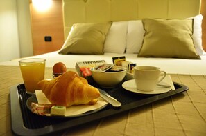 Aamiaistarjotin, jossa on croissantteja, appelsiinimehua, kahvia ja sanomalehtiä, hotellin sängyllä.