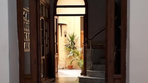 A hallway with a marble floor, wooden doors, and a staircase leading to another level.