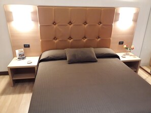 A bed with a tufted headboard, two bedside tables, and a nightstand with a vase of flowers. - Terrazza Cola Di Rienzo - Two Bedroom (Rome)