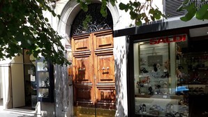 A storefront with a large wooden double door, a glass display window with shoes, and a sign reading 'SALDI'.