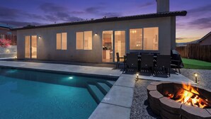 Una casa moderna con piscina, area salotto esterna e un braciere.