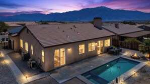 Una casa moderna con piscina, ampie finestre e vista sulle montagne.