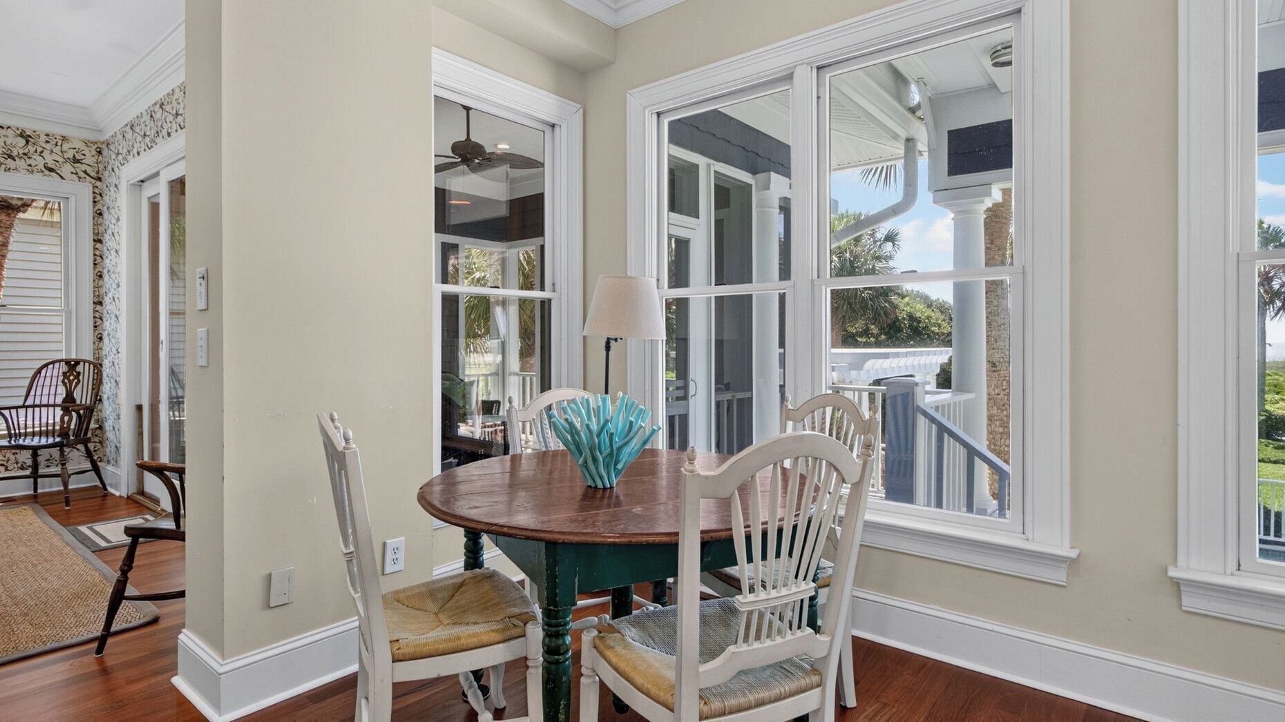 A dining area with a table and chairs, large windows, and a view of the outdoors.