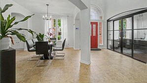 Um interior espaçoso com área de refeições, uma porta vermelha e vista através de uma parede de vidro.