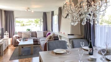 A dining area with a table set for two, a chandelier, and a sofa in the background.