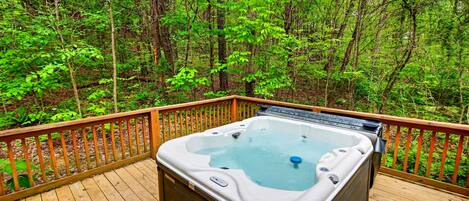 A hot tub on a wooden deck surrounded by a forest.