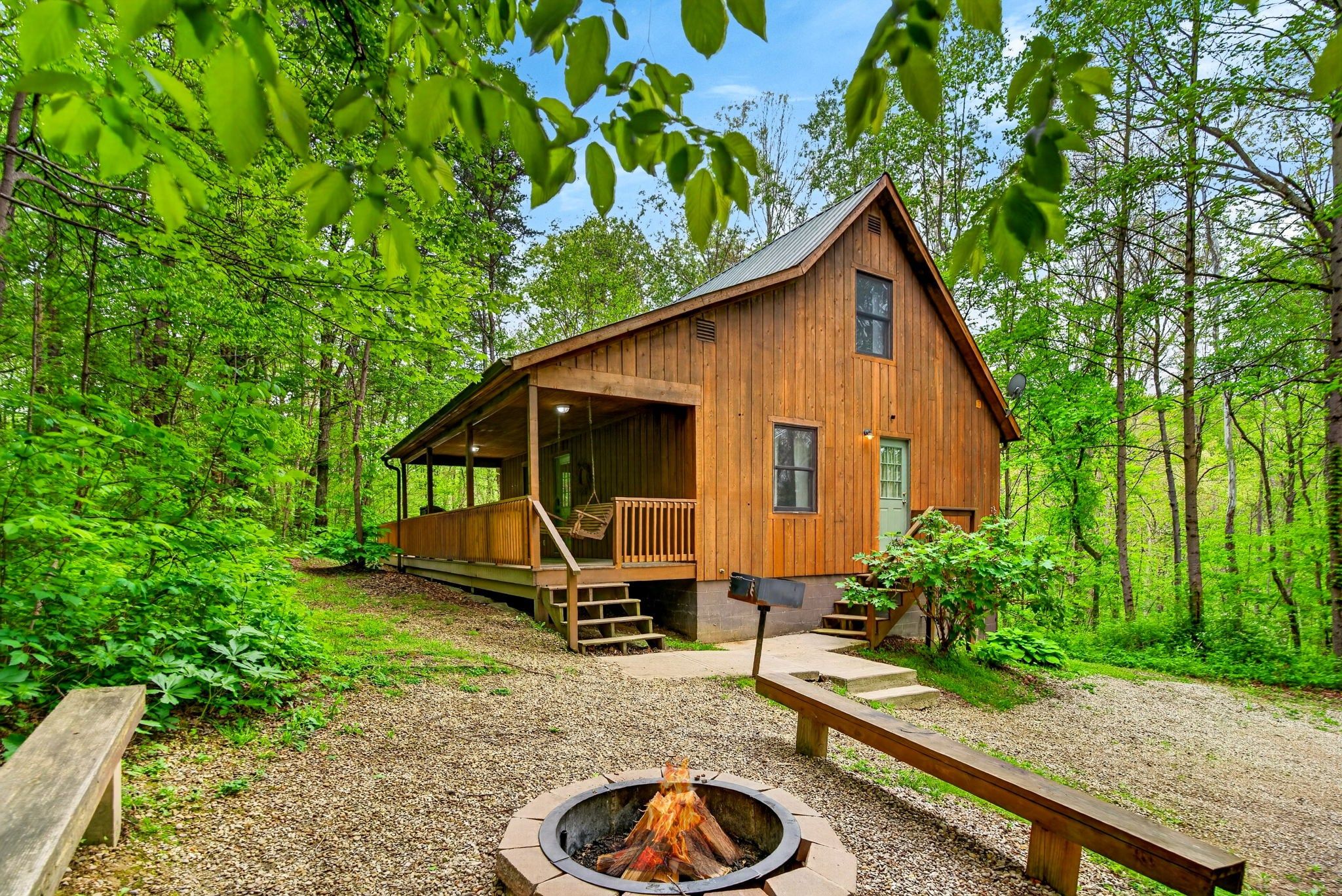 Une cabane en bois dotée d’une véranda, d’un foyer et d’un escalier menant à l’entrée.