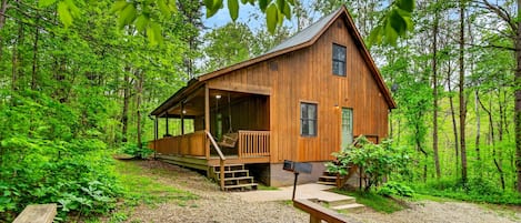 A wooden cabin with a porch, a fire pit, and a staircase leading to the entrance.