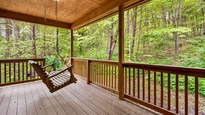 A wooden deck with a hanging chair, surrounded by a railing, overlooking a forested area. - Turkey Run, Cozy Woodland Cabin Retreat in the Heart of Hocking Hills, Hot Tub (Logan)