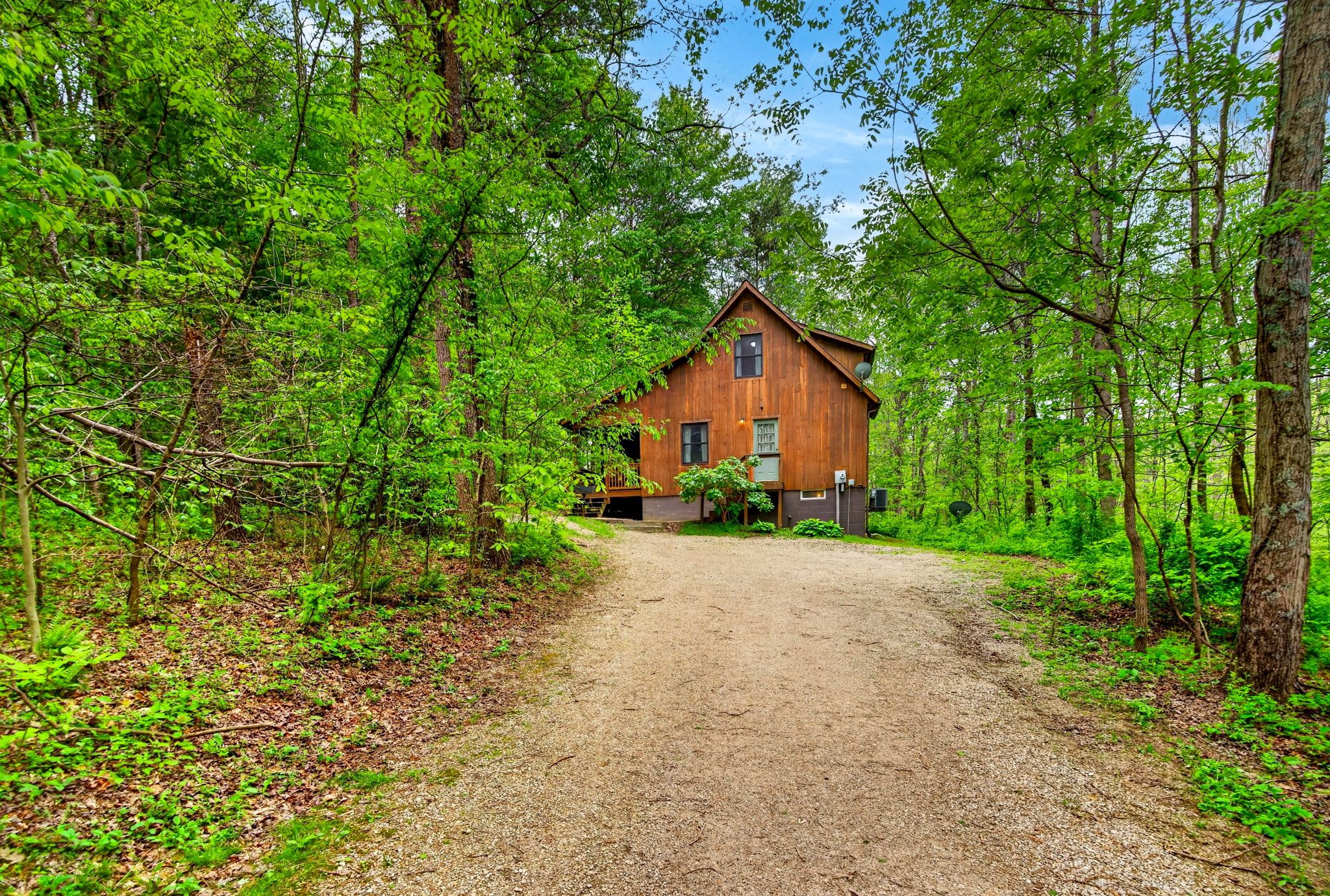 A rustic wooden cabin surrounded by dense forest.