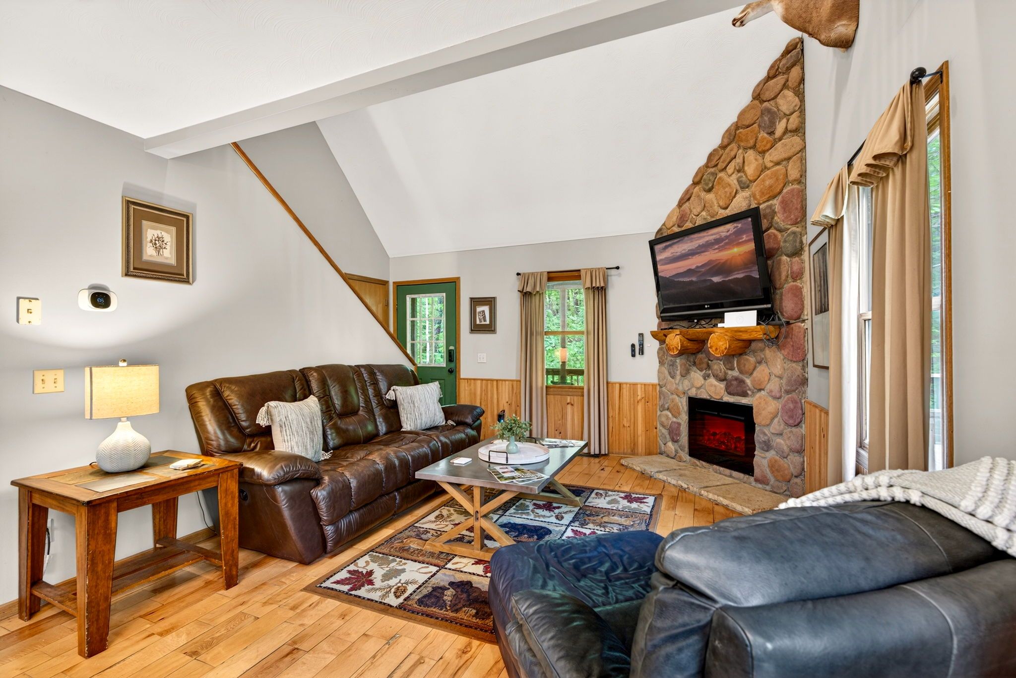 A cozy living room with a stone fireplace, leather sofas, and a television.