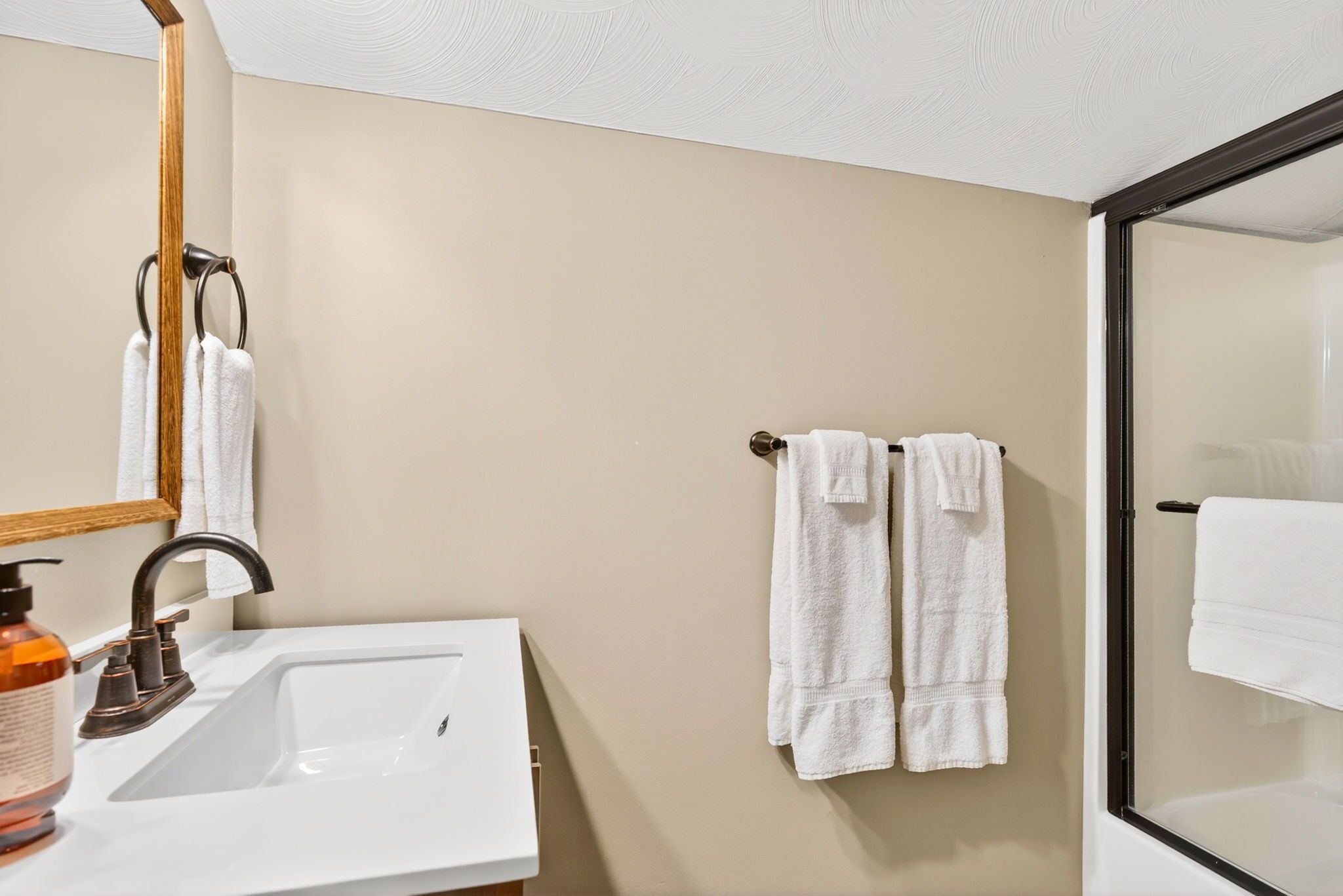 A bathroom with a white sink, a mirror, and two towels hanging on a towel rack.