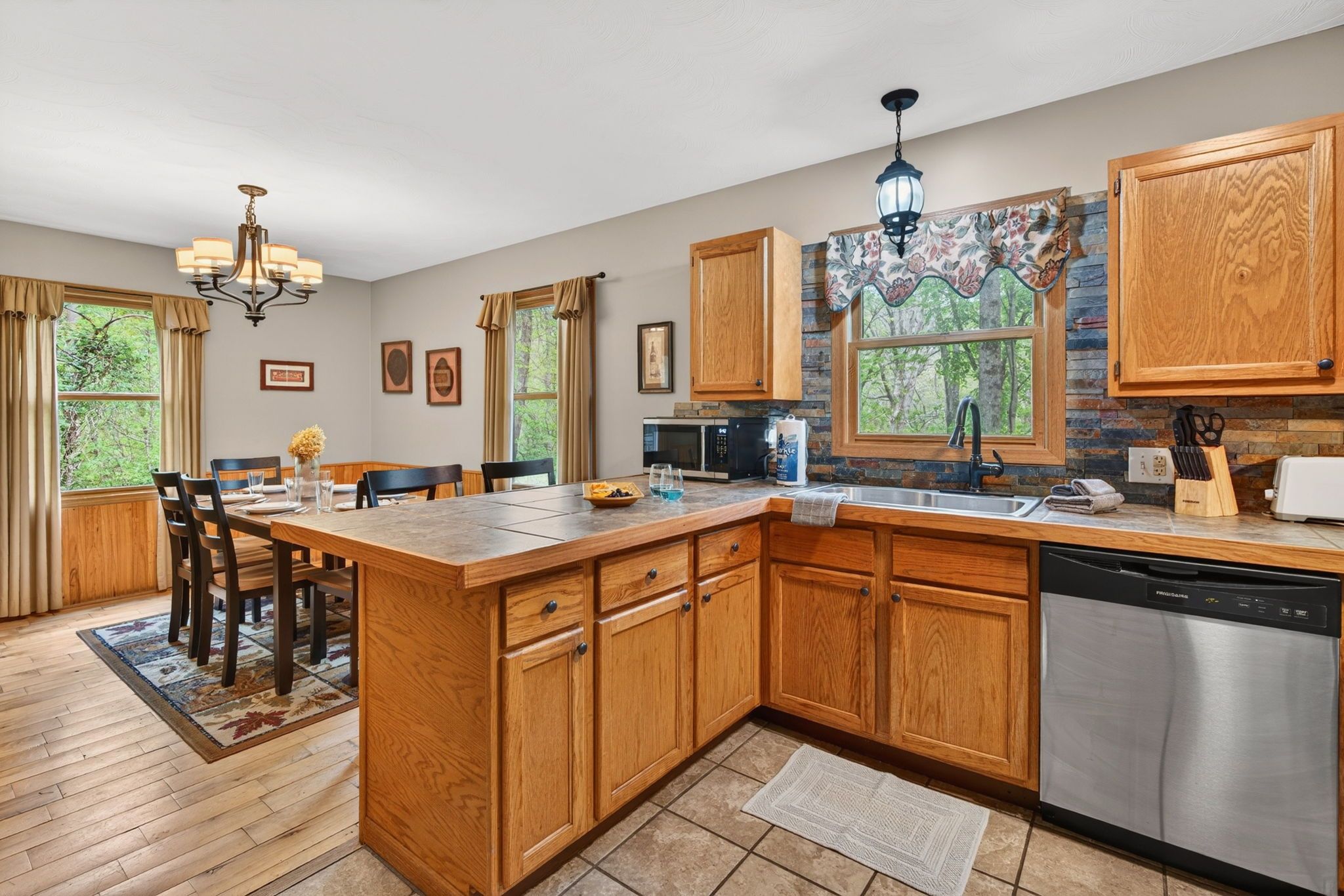 A kitchen with wooden cabinets, a central island, a built-in dishwasher, and a stone backsplash.