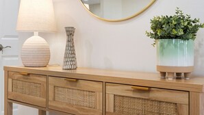 En trækommode med et rundt spejl, en lampe, en vase og en potteplante.