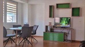 A room with a dining table, chairs, a television, and a green cabinet. - Aerodrom District 1-Bed Apt, Sleeps 2 with Parking (Skopje)