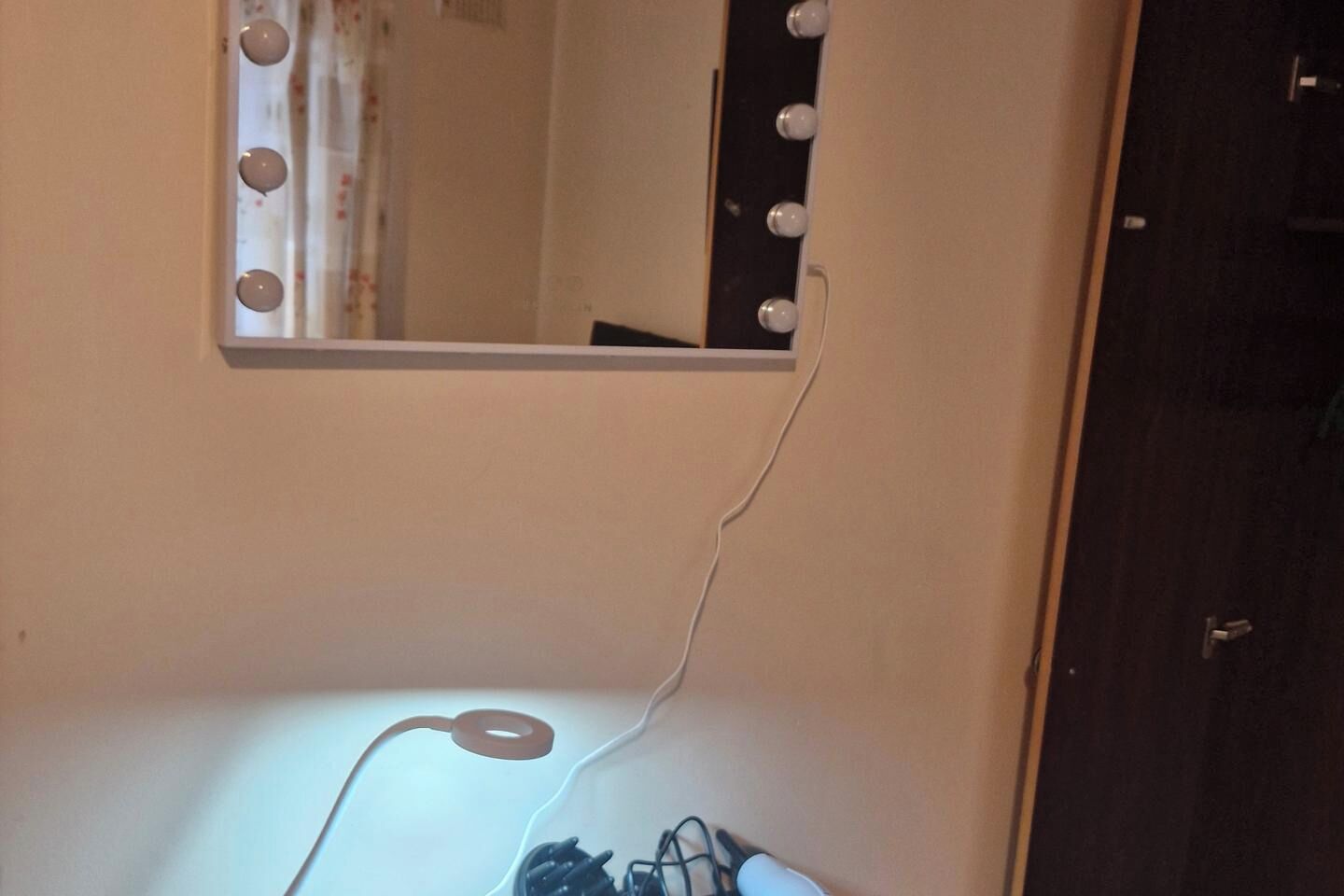 Une pièce avec un miroir de coiffeuse, une lampe et une porte.