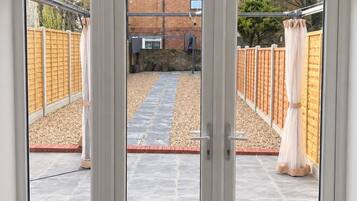 A sliding glass door leading to an outdoor patio area with a brick wall, a wooden fence, and a stone pathway.