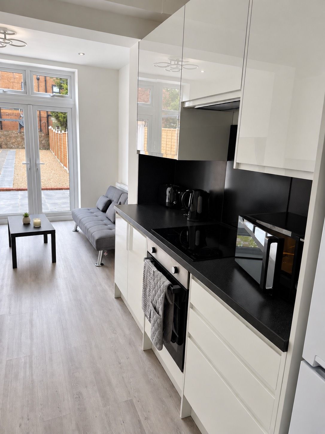 A modern kitchen with white cabinets, a black countertop, and a built-in oven.