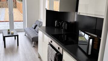 A modern kitchen with white cabinets, a black countertop, and a built-in oven.