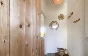 A hallway with wooden walls, a white brick wall with decorative mirrors, and a wicker basket. - Awesome home in Lauwersoog (Lauwersoog)