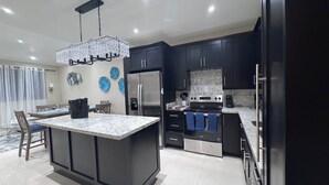 A modern kitchen with dark cabinets, stainless steel appliances, and a central island.