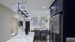 A modern kitchen with a granite countertop, stainless steel appliances, and a dining area with a table and chairs.