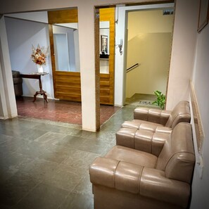 A modern interior with a leather sofa, a wooden bench, and a tiled floor.