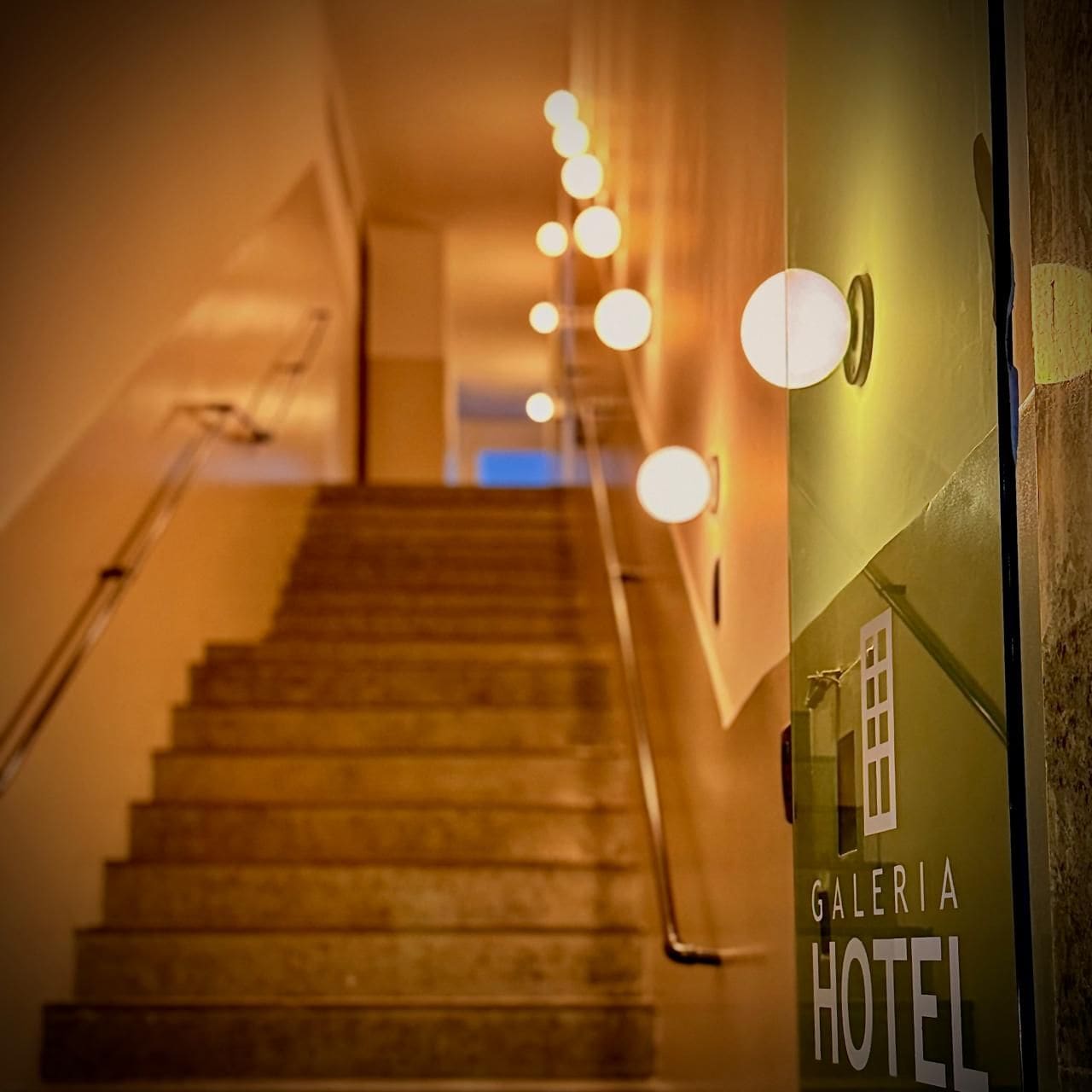 A staircase leading to a hotel entrance with a sign reading 'Galeria Hotel'.