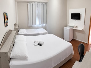 Une chambre d’hôtel avec deux lits, une télévision, un bureau et un petit réfrigérateur.