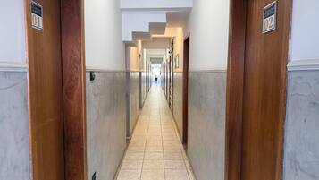 Corredor de hotel com portas numeradas 01 e 02, dando acesso aos quartos.