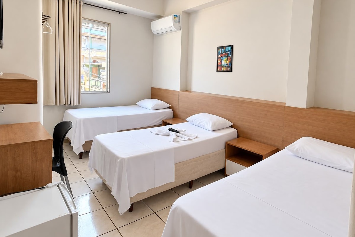 Une chambre d’hôtel avec deux lits simples, un bureau et une chaise.