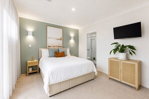 A bedroom with a bed, bedside tables, a TV, a plant, and a shower. - The Duchess of Duke | Spa, Sauna & Beach Walk (Scarborough)