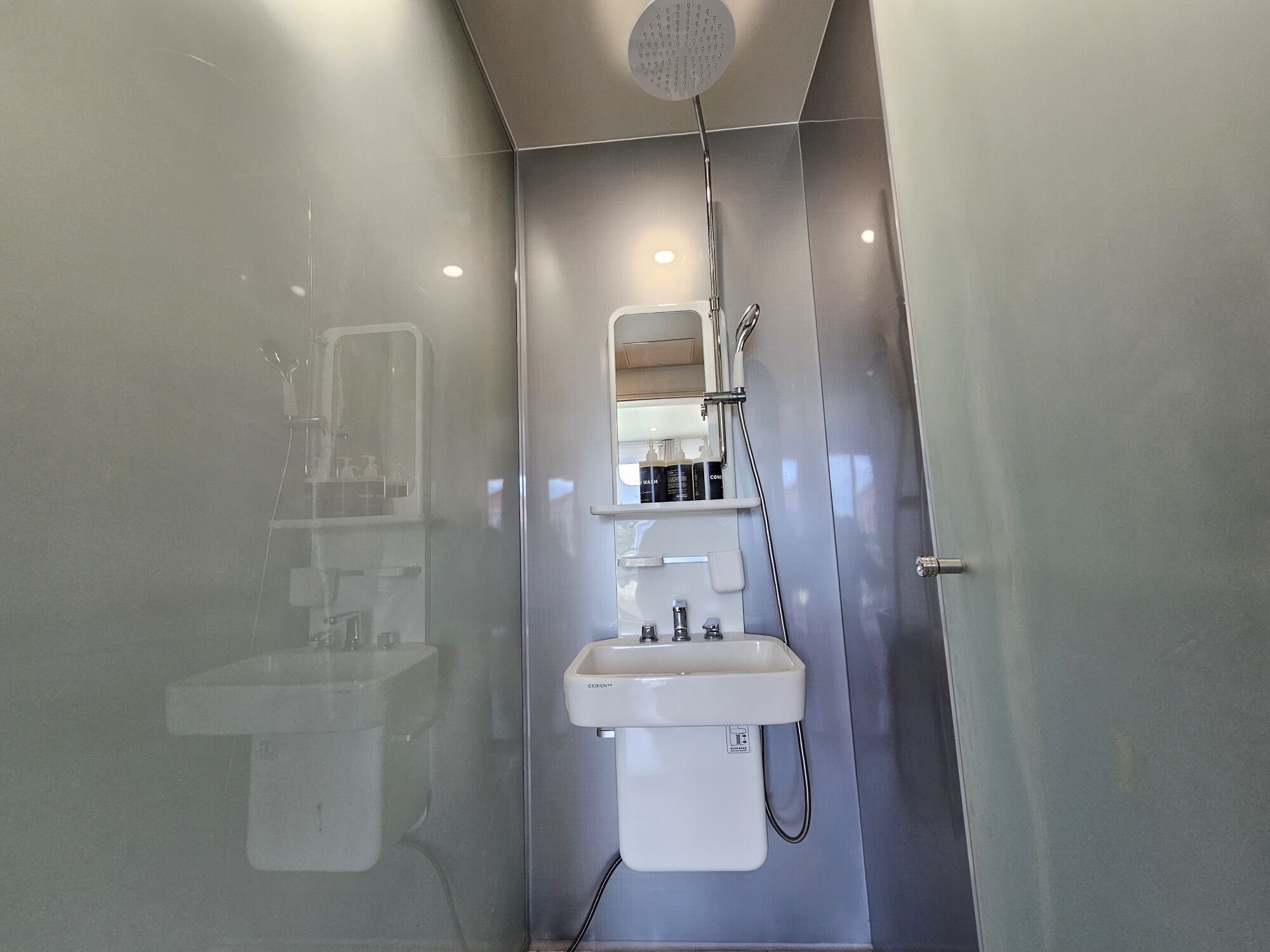 Un baño moderno con cabina de ducha de vidrio, lavabo y espejo.