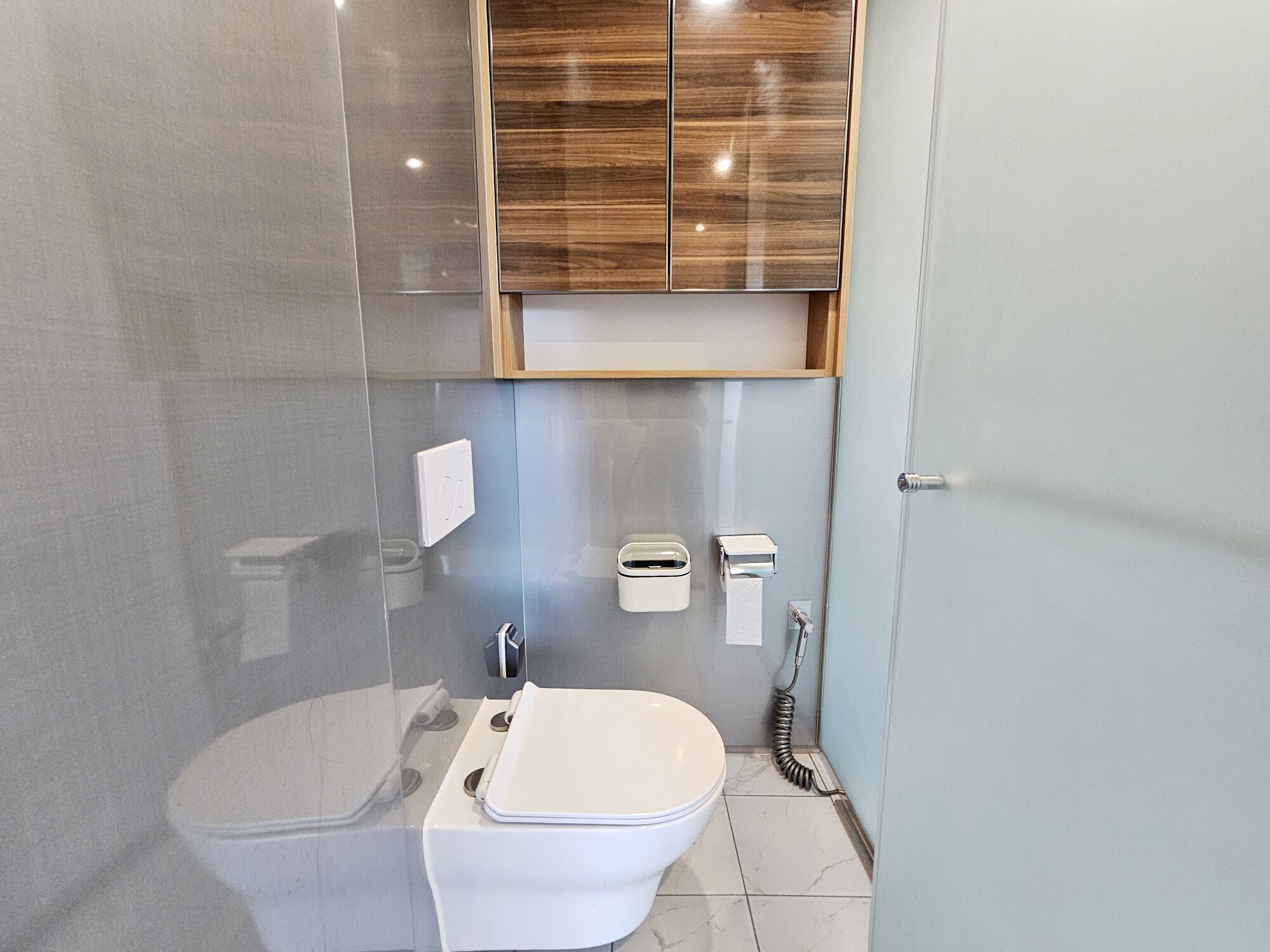 A modern bathroom with a toilet, bidet, and a shower area.